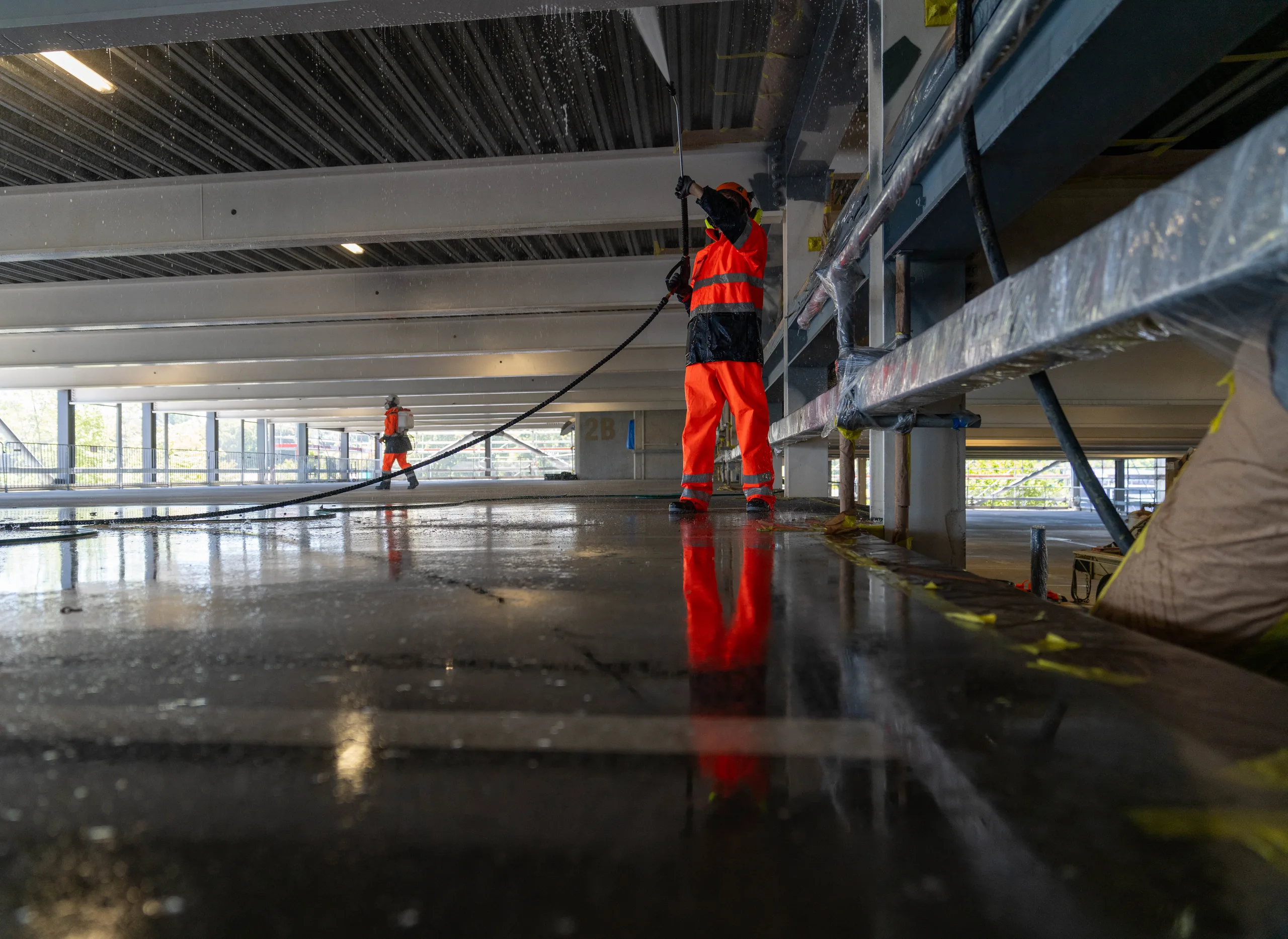 Connect Group operator hydro-blasting a structural concrete deck under containment screens.