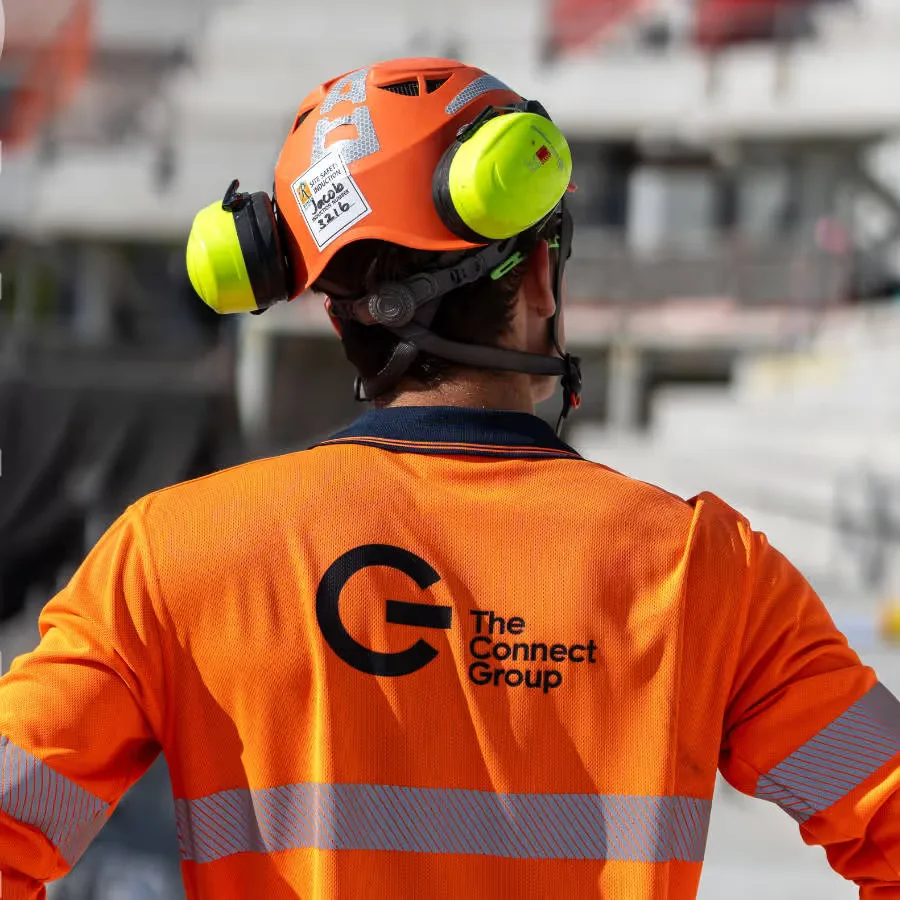 A Connect Group worker from behind in branded orange hi-vis and hard hat