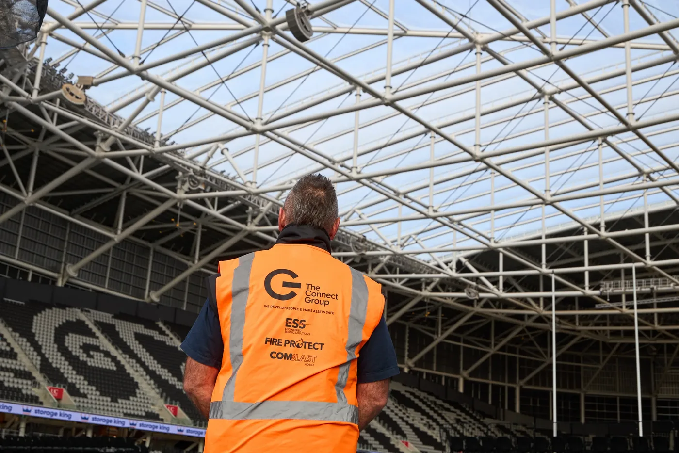 A worker looking up at the stadium's glazed roof structure